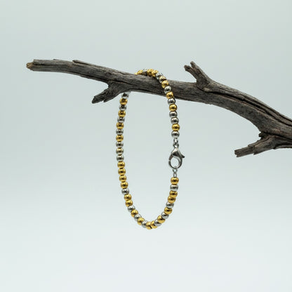 Aramat Jewels bicolor stalen kralenarmband van 19cm met zilver- en goudkleurige bolletjes aan een tak.