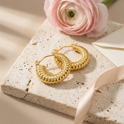 Aramat Jewels gold-coloured stainless steel hoop earrings with a ribbed texture, 20mm diameter.