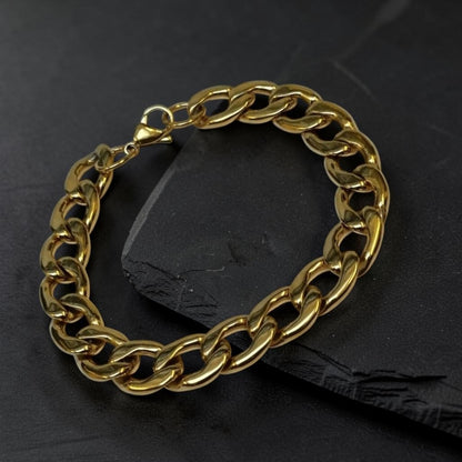 Aramat Jewels goudkleurige stalen gourmetarmband met steentjes op een zwarte leistenen ondergrond.