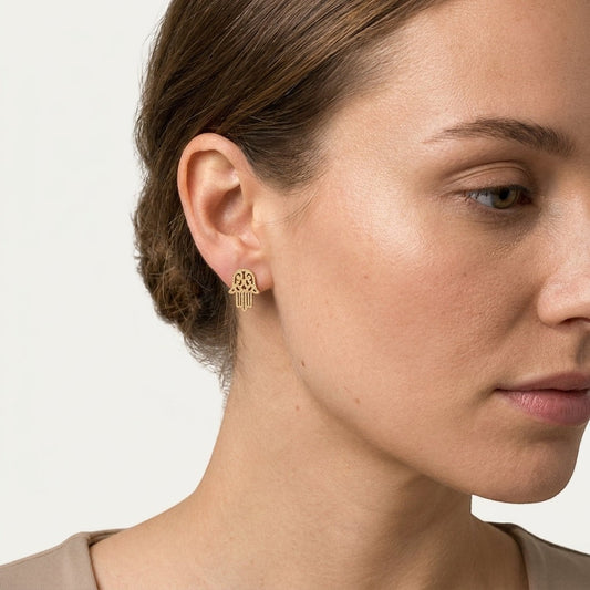 Aramat Jewels goudkleurige Hamsa oorstekers van RVS met een matte, gezandstraalde afwerking gedragen door een model.