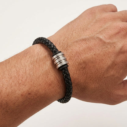 Aramat Jewels stoere zwarte gevlochten leren herenarmband met een zilverkleurige RVS kraal om een pols.