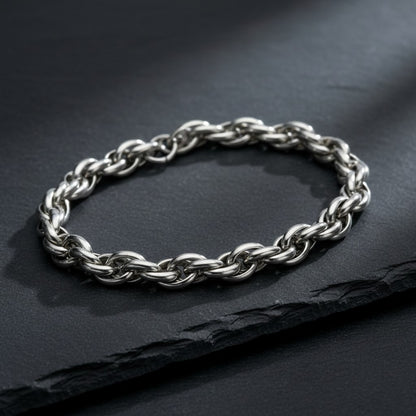Zilverkleurige Aramat Jewels gevlochten armband van RVS, 7 mm breed en 22 cm lang, gepresenteerd op een zwarte ondergrond