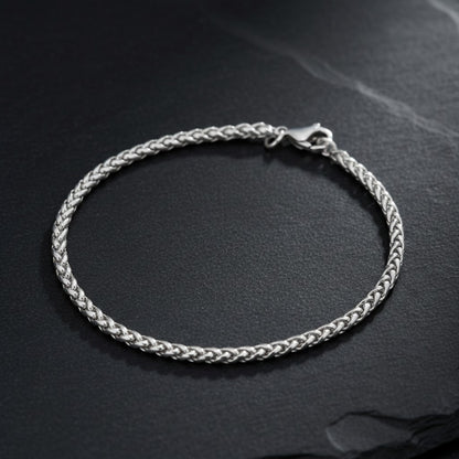 Aramat Jewels vossenstaart armband van zilverkleurig RVS met een verfijnde schakel op een donkere ondergrond.