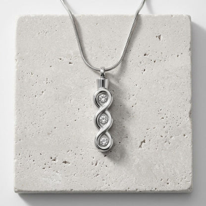 Aramat Jewels zilverkleurige stalen crematiehanger met transparante details en een infinity design.