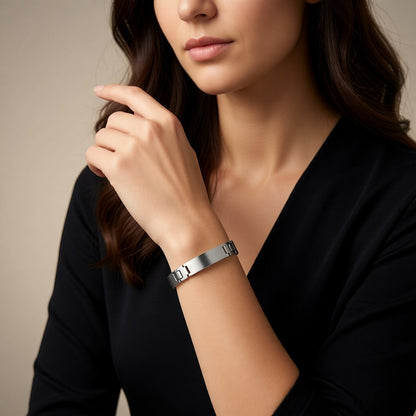 Aramat Jewels zilverkleurige stalen plaatarmband van 12mm breed gedragen door een vrouw in een zwarte top.