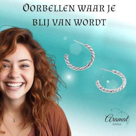 Lachende vrouw draagt zilverkleurige Aramat Jewels halve oorringen met een elegant gedraaid motief van roestvrij staal.