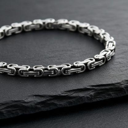 Aramat Jewels zilverkleurige RVS koningsschakel armband van 5mm breed en 20cm lang op een zwarte leistenen ondergrond.