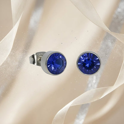 Aramat Jewels zilverkleurige oorstekers met donkerblauw kristal van 7mm, gemaakt van roestvrij staal.