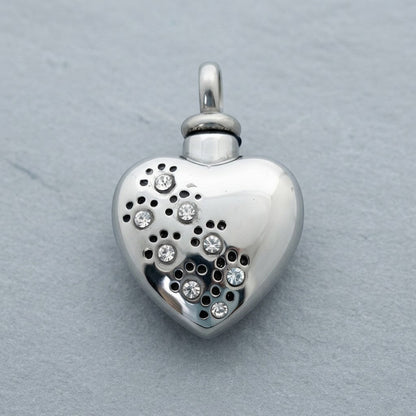 Aramat Jewels zilverkleurige stalen ashanger in hartvorm met zirkonia pootjes en perforaties.