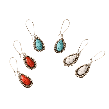 Drie paar druppelvormige oorbellen met edelstenen in turquoise, rode en witte kleuren, gezet in een sierlijk metalen montuur.
