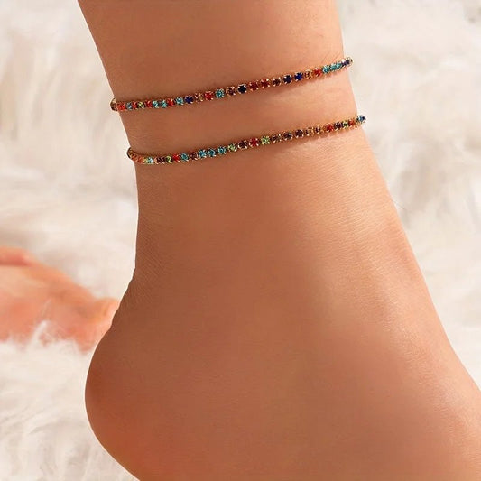 Een vrouw die een gouden armband met veelkleurige stenen draagt