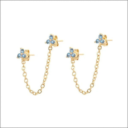 Een paar gouden ketting oorbellen met blauwe kristallen