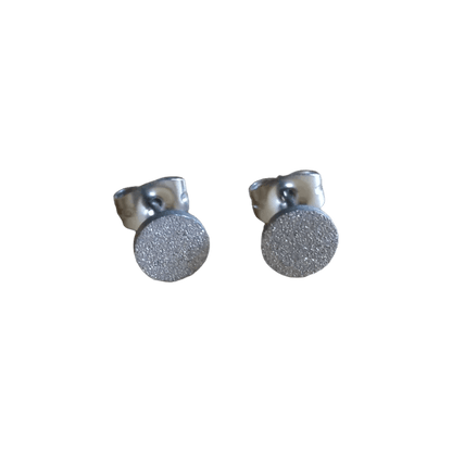 Paar zilveren oorstekers met gestructureerde ronde vlakken.