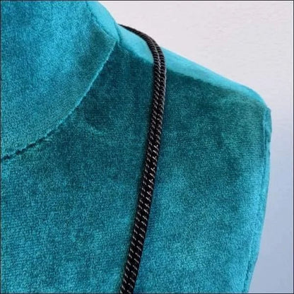 Een blauw fluwelen jurk met een zwarte ketting
